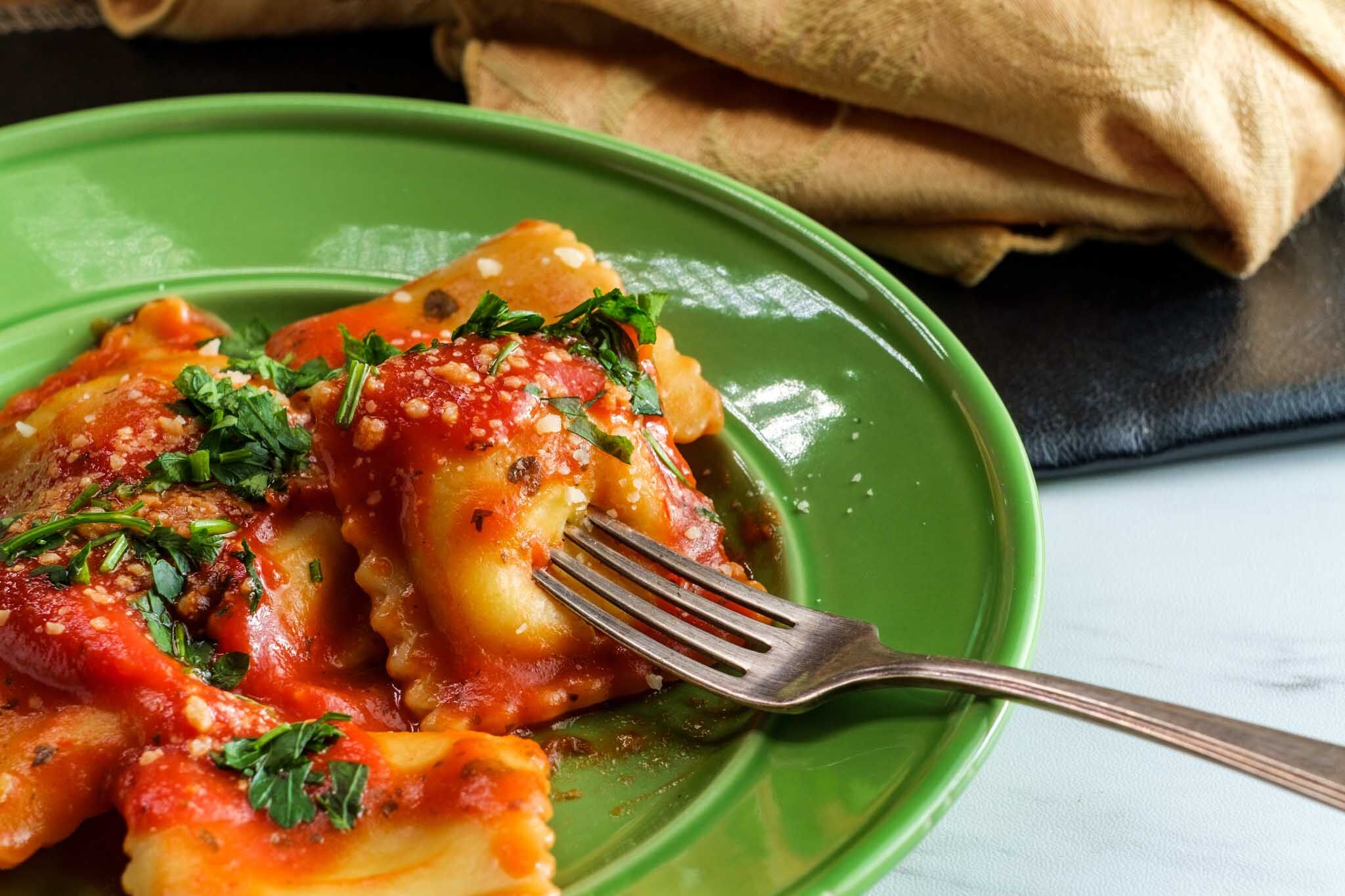 Fresh made cheesy raviolis on a green plate at The Real Food Academy Miami.