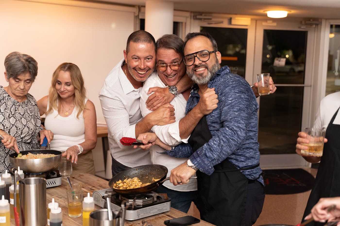 A group of friends hugging and laughing at one of The Real Food Academy's adult cooking classes.