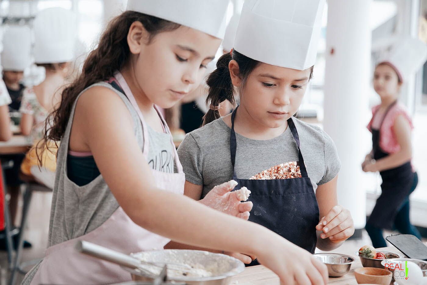 Two girls working on their magical creation at The Real Food Academy's kids cooking camp.
