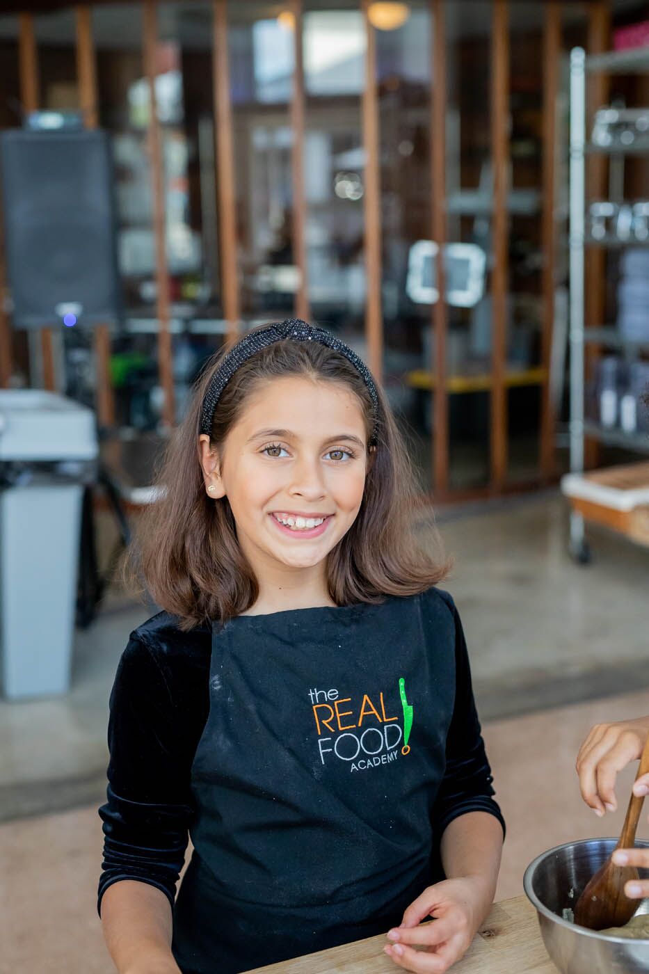 A younger girl at a kids cooking camp with The Real Food Academy - a perfect place to meet friends!