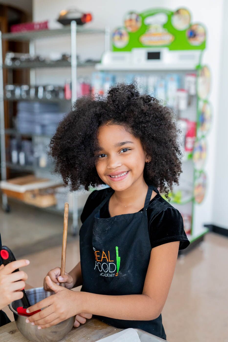 A young girl mixing up magic in a bowl at The Real Food Academy kids cooking camps.