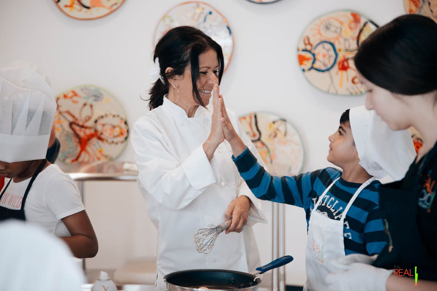 Chef Maria giving a kid a high five at The Real Food Academy's kids cooking camp.