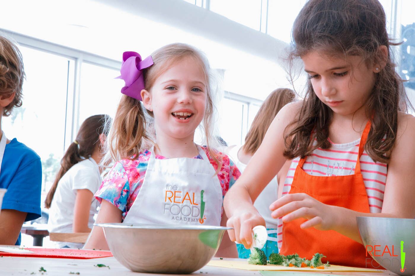 A group of young kids rolling out fresh dough, contact us today for more kids and teens cooking classes.