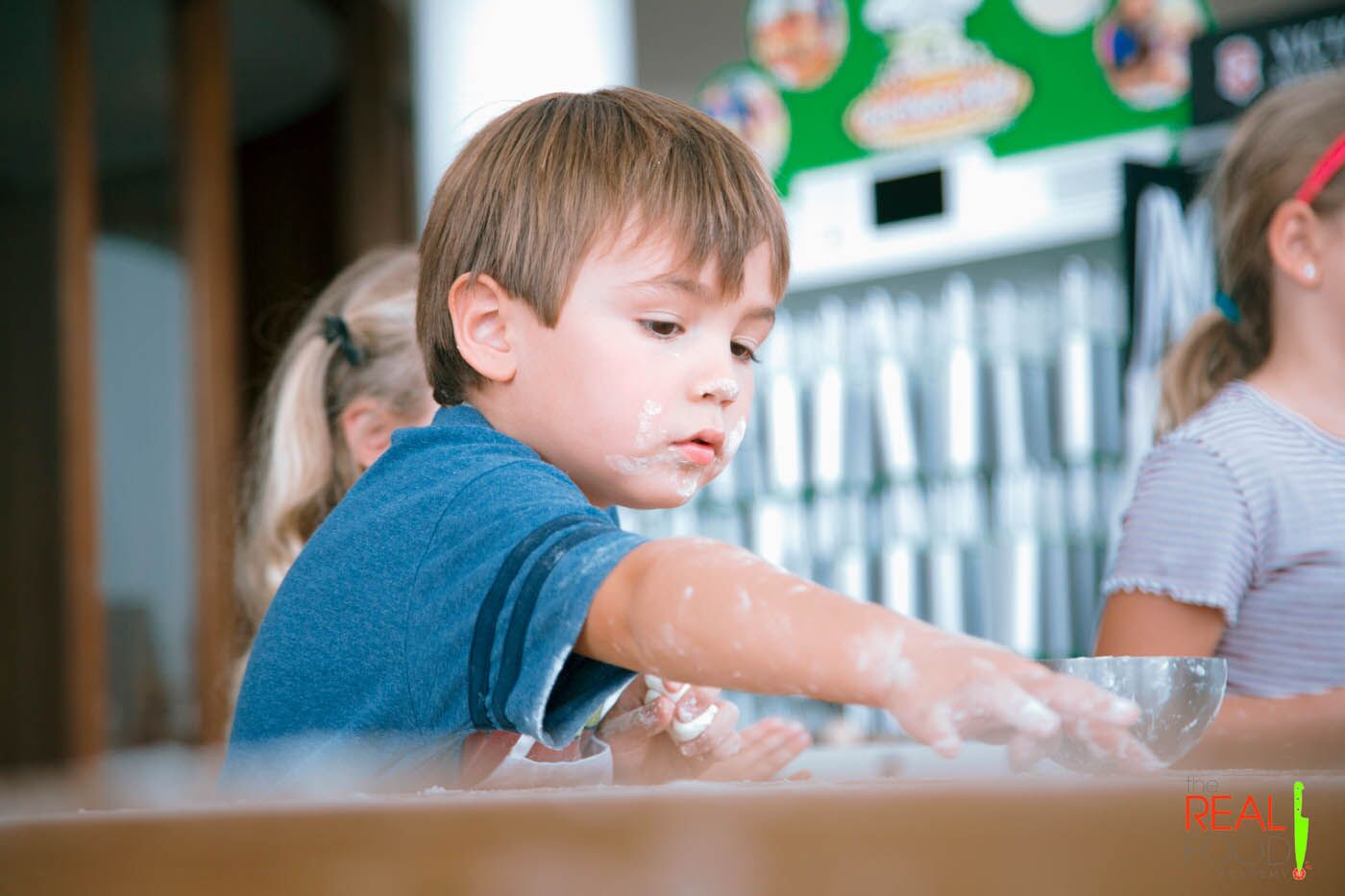 A little kid with flower on his face practicing his cooking skills at The Real Food Academy's after school program.