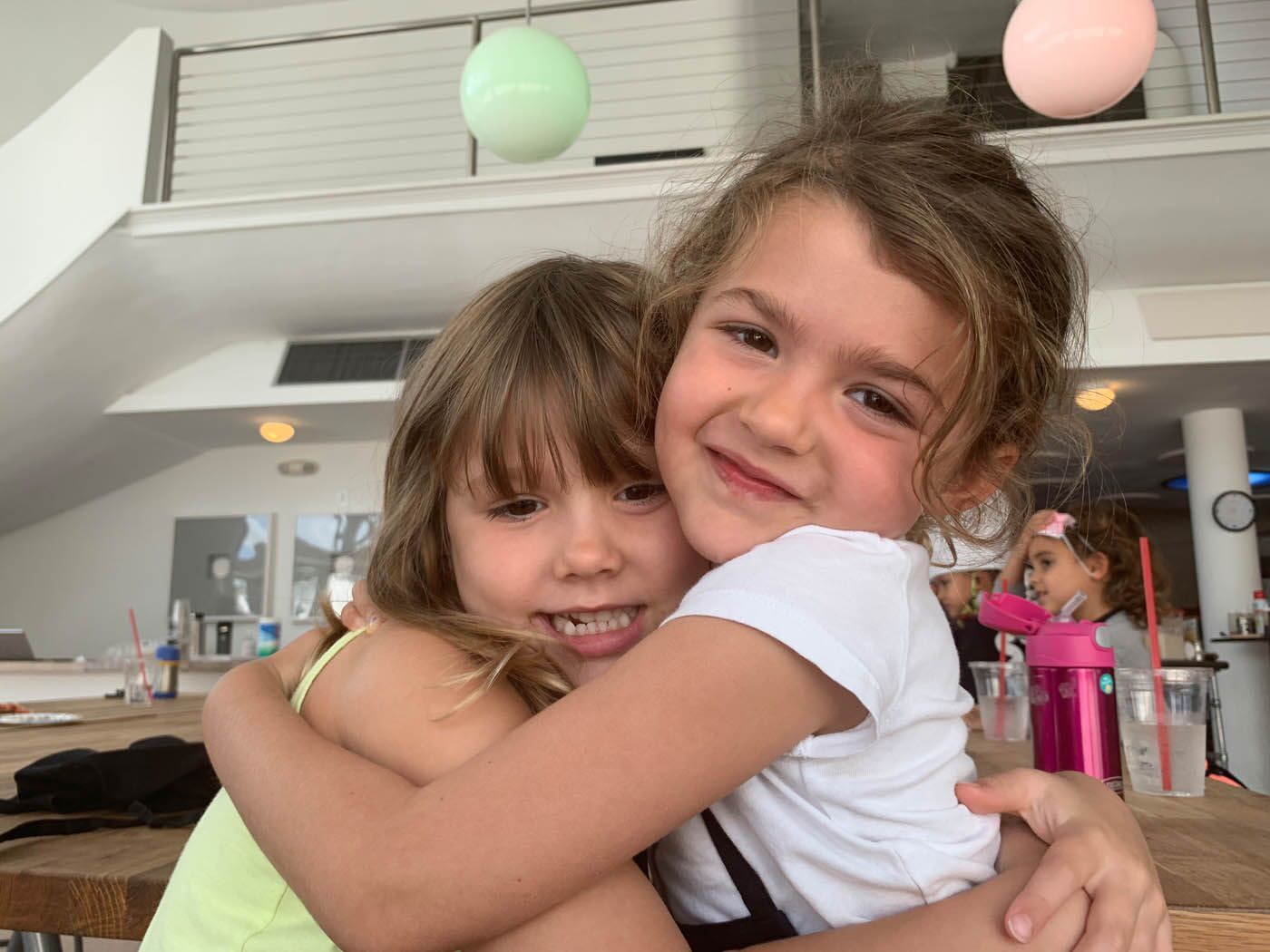 Two young girls hugging at The Real Food Academy's kids and teens cooking class.