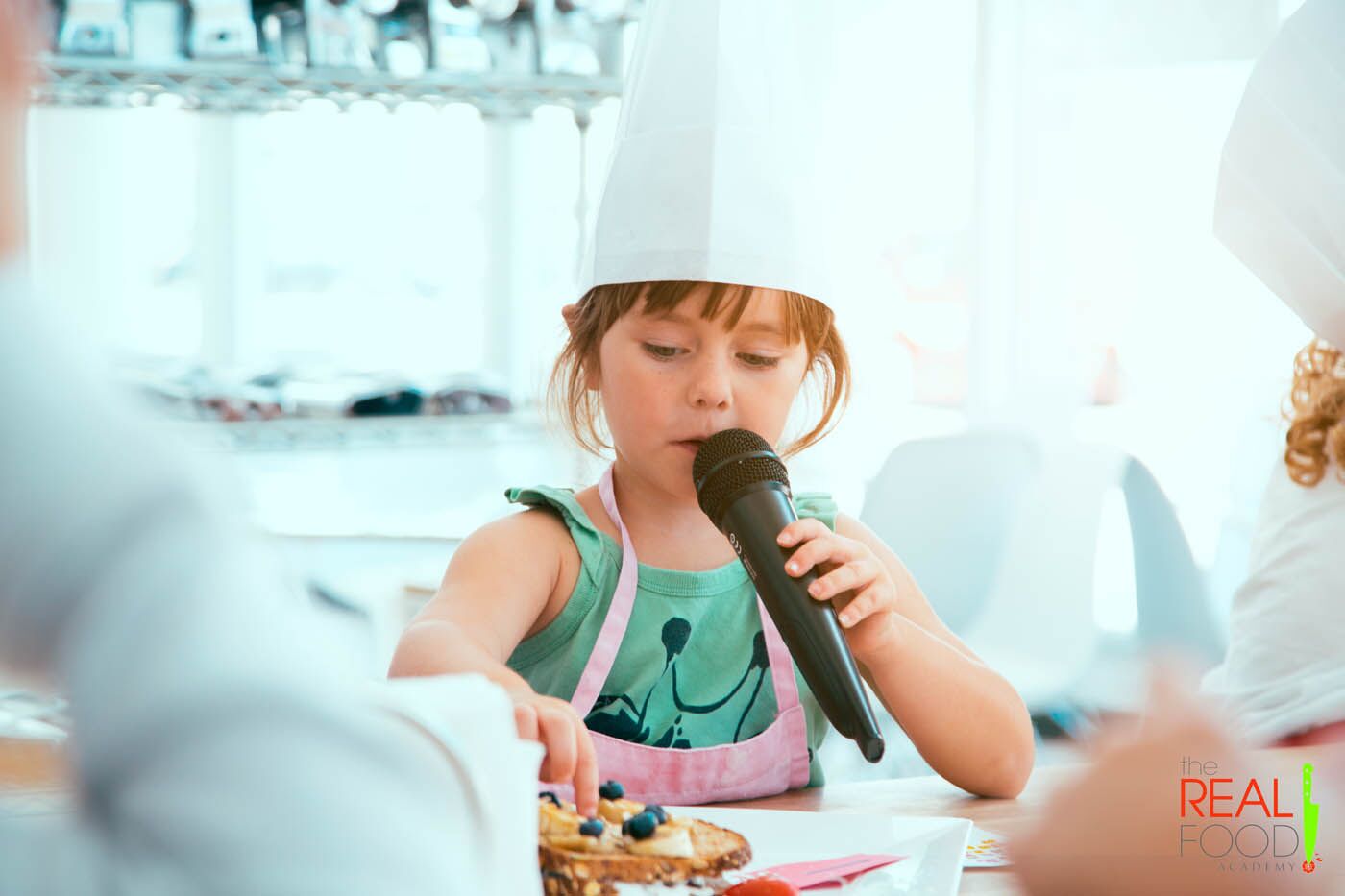 A young girl with a microphone at The Real Food Academy's kids cooking camp.