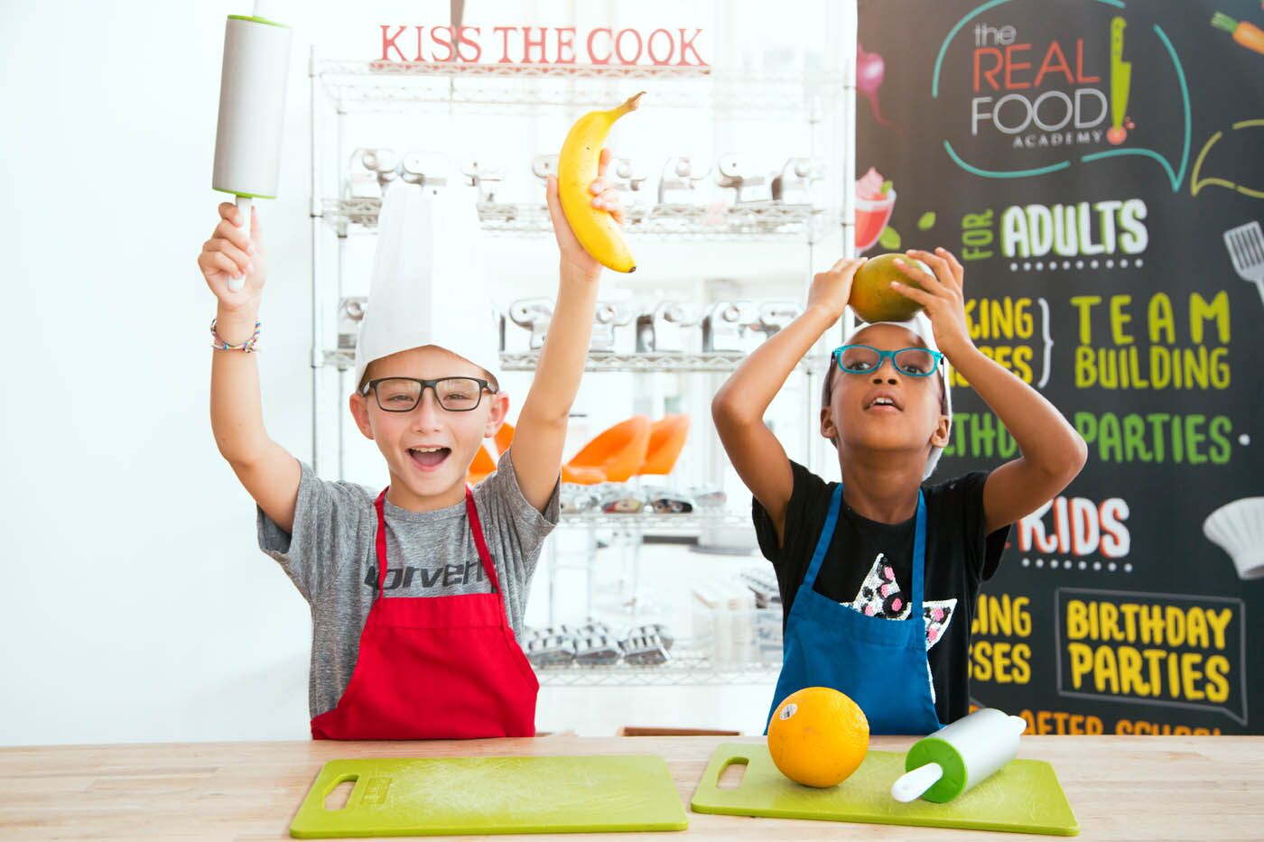 Two little boys playing with fruit at The Real Food Academy's day cooking camps.