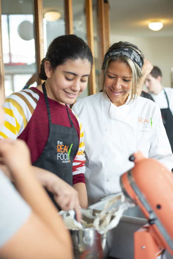 Chef Maria Cummins and a teenager cooking together at our summer camp for teens.