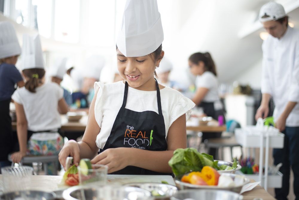 An image of a young girl cooking at The Real Food Academy's weekend and afterschool programs - kids activities. 
