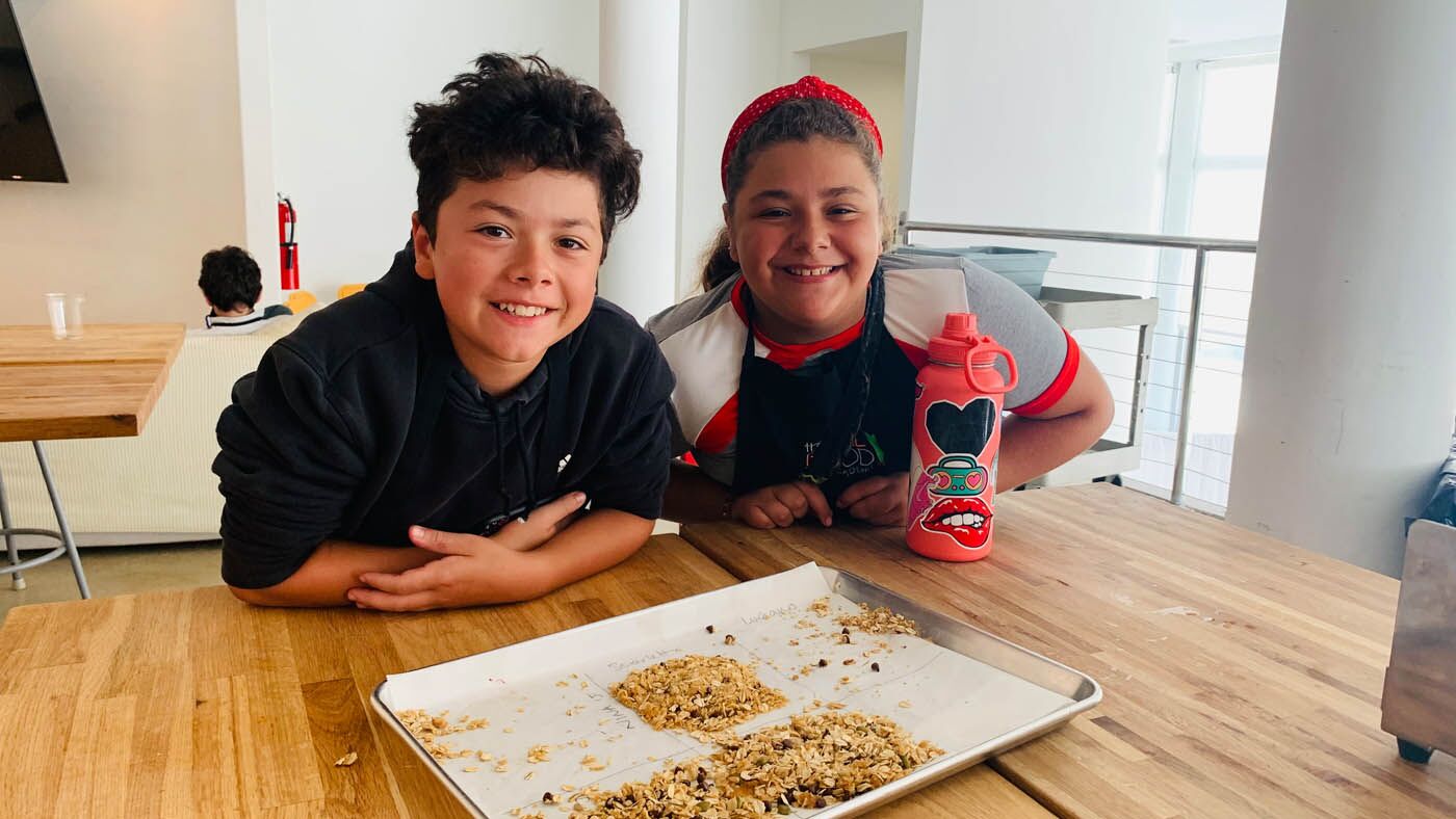 Two children posing with homemade granola from a The Real Food Academy cooking camp.