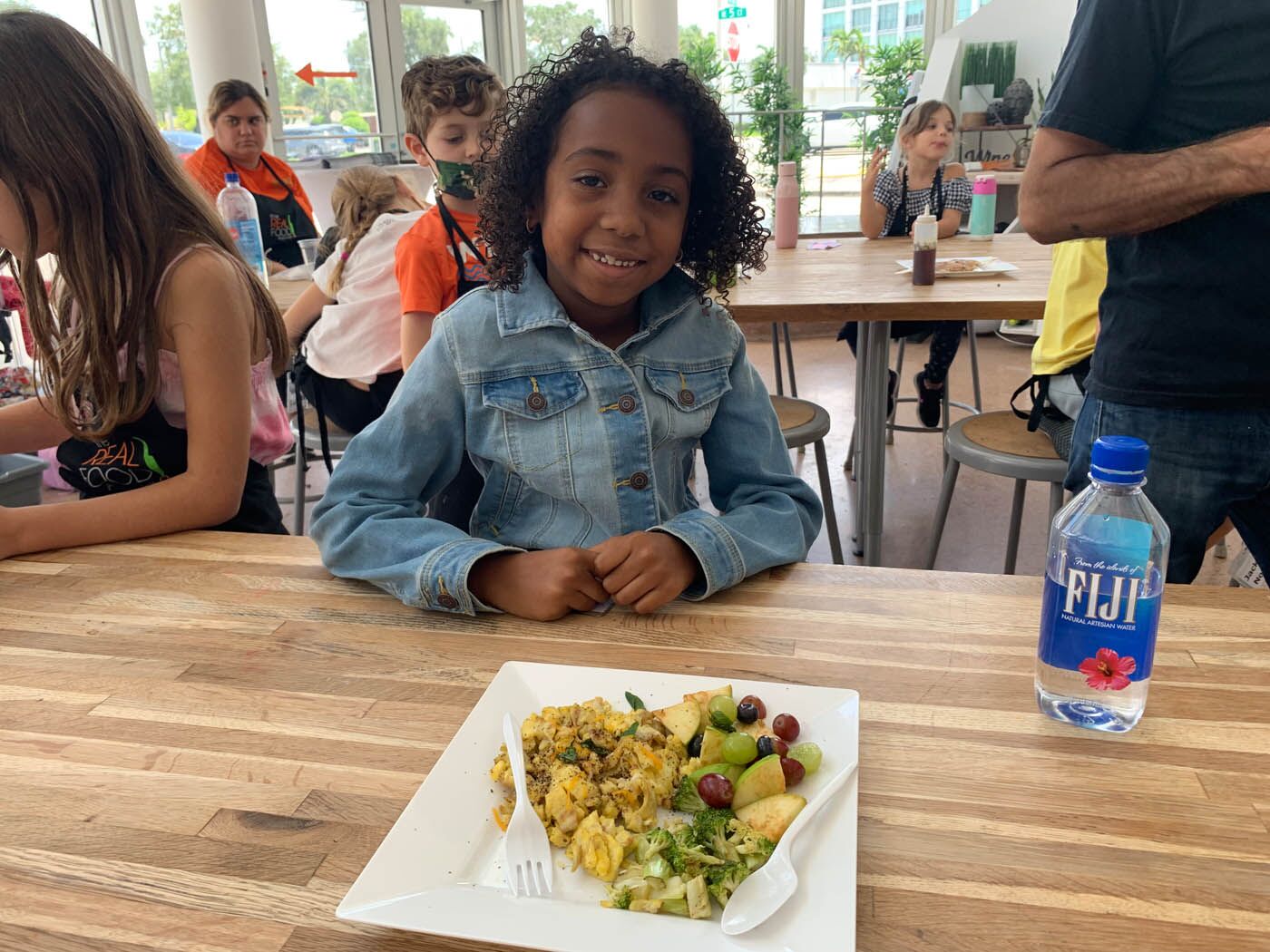 A little girl at The Real Food Academy's after school program with a fresh plate of fruits and veggies.