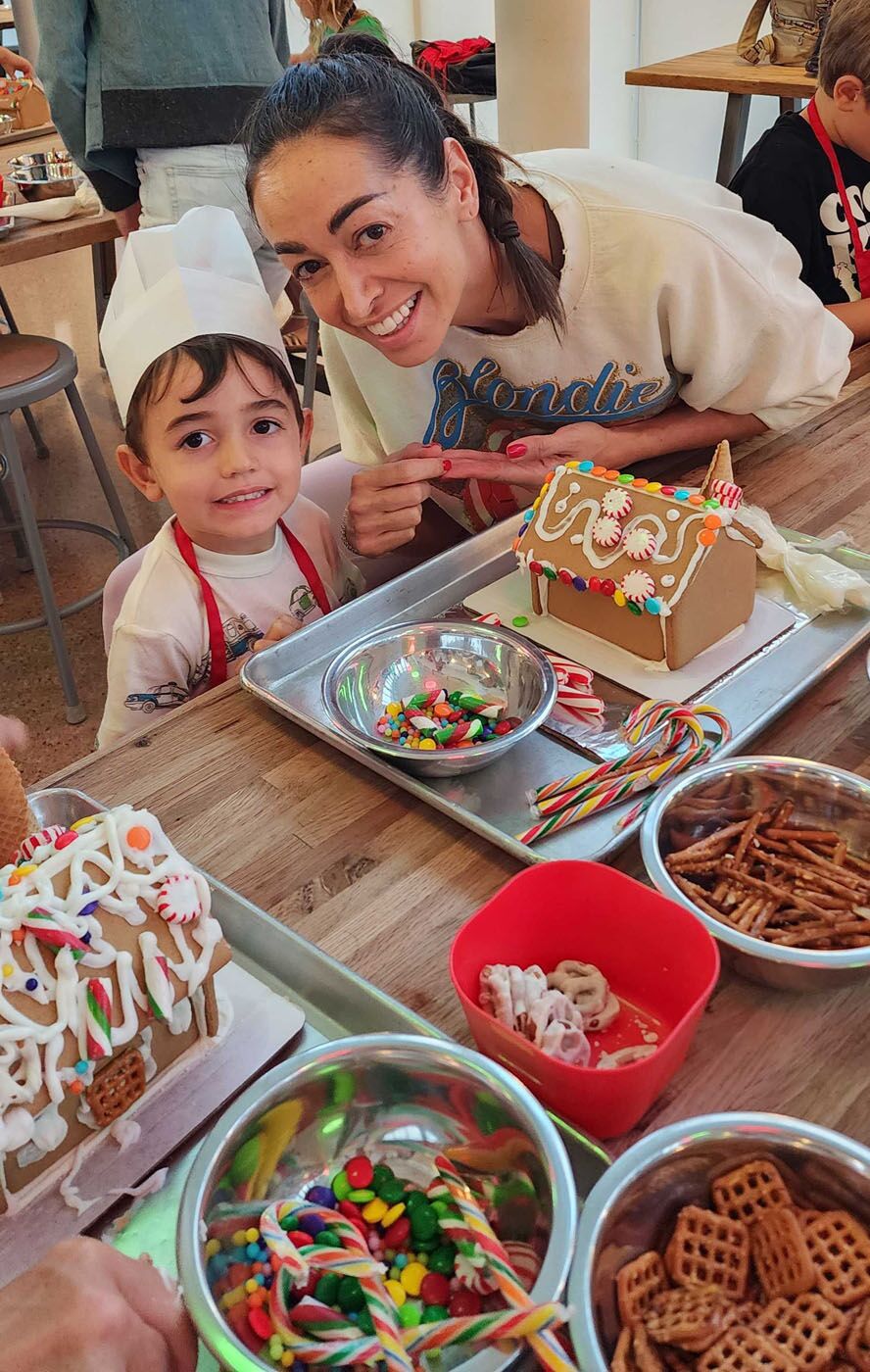 A kid and his adult building gingerbread houses together at The Real Food Academy!