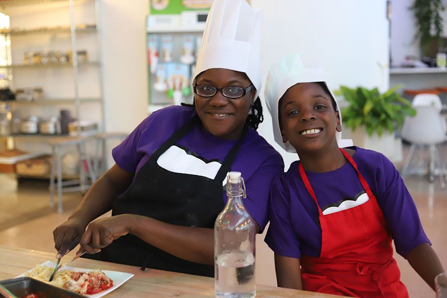 A mom and son in purple shirt participating at one of {fran_brand_names}'s mommy and me cooking classes.