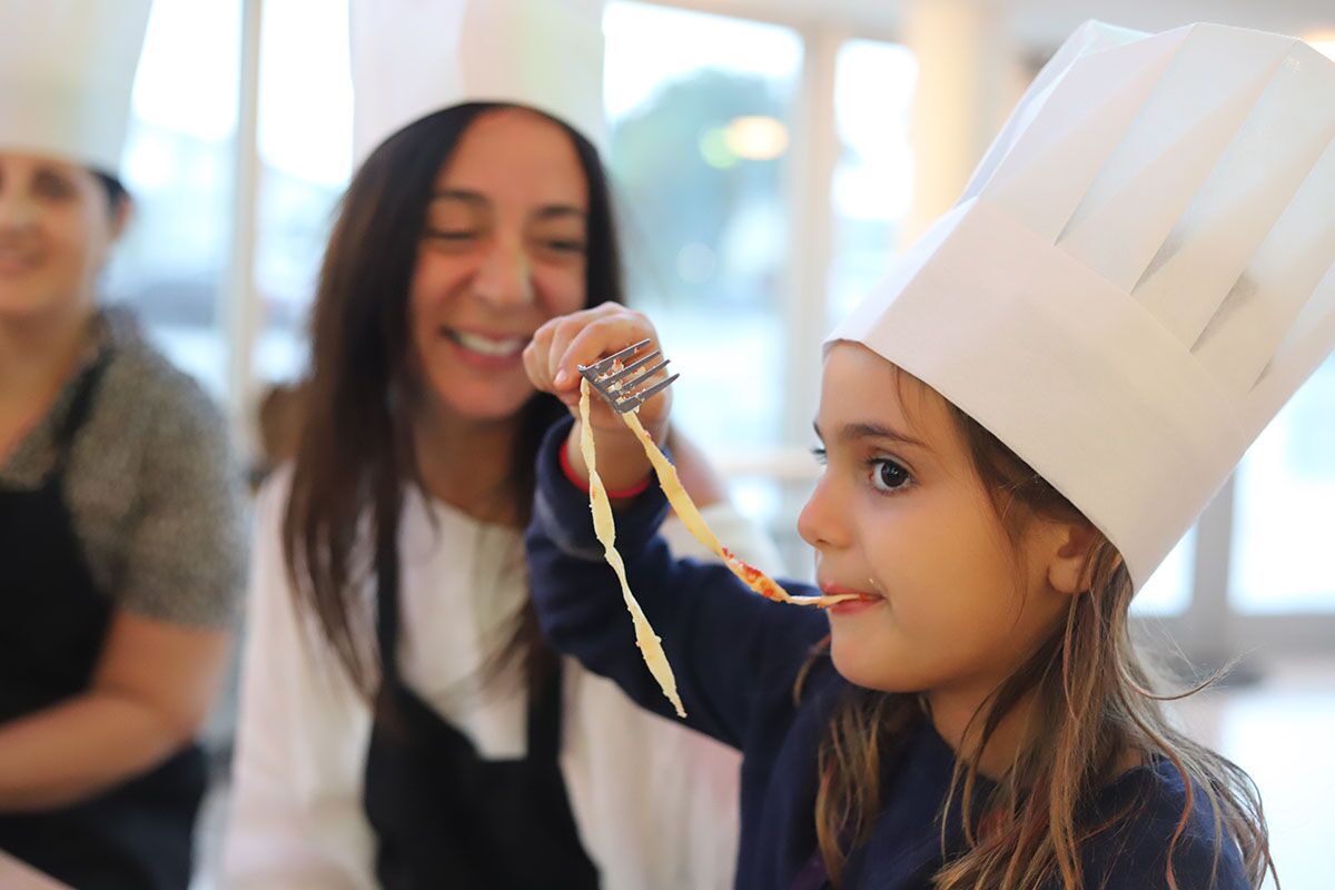 A mom and daughter eating spaghetti and one of {fran_brand_names}'s mommy and me classes.