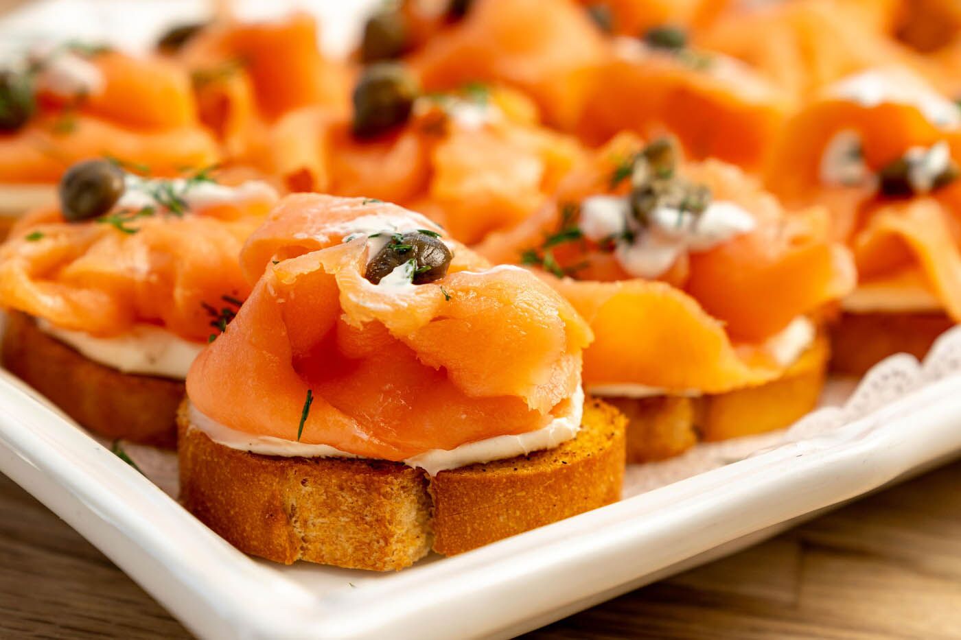 Smoked salmon with a side of capers in a white plate at The Real Food Academy.